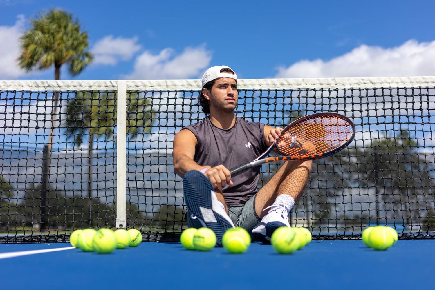 A player sitting at the net with a Diadem racket and tennis balls